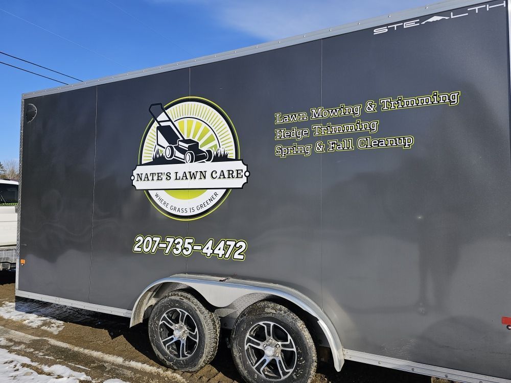 A trailer with a lawn mower on it is parked in the snow.