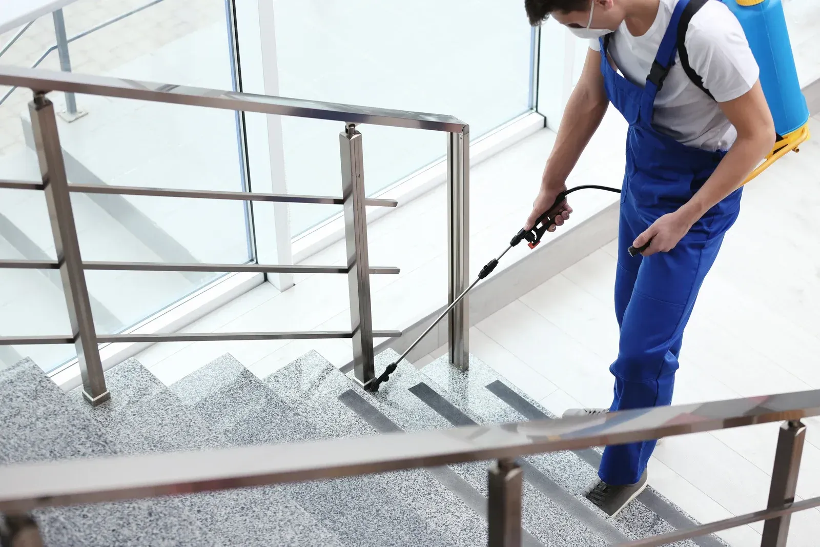 A man is spraying a staircase with a sprayer.