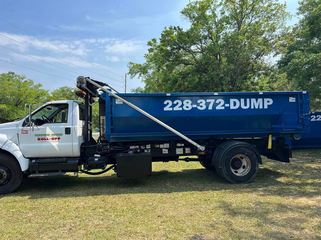 A dump truck is parked in a grassy field.