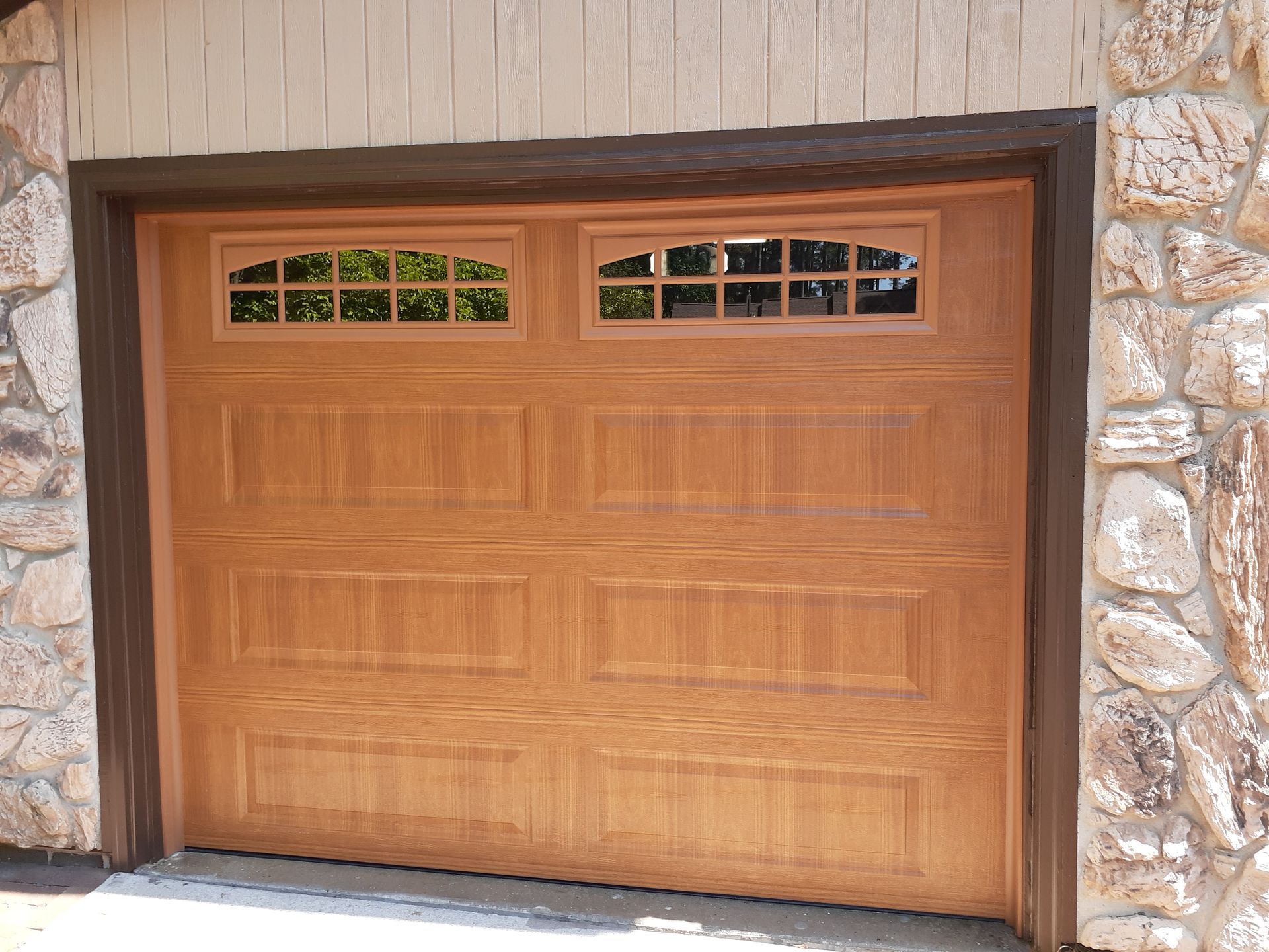 a wooden garage door with a stone wall behind it .