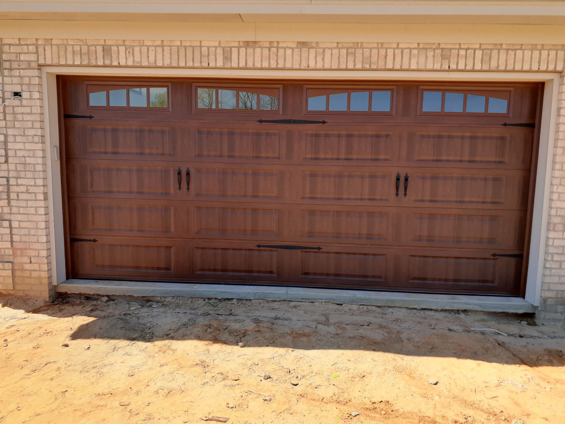 a large wooden garage door is sitting in front of a brick building .