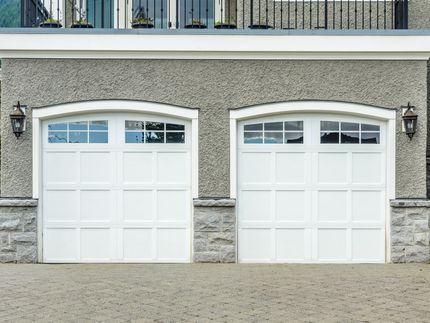 there are two white garage doors on the side of a house .