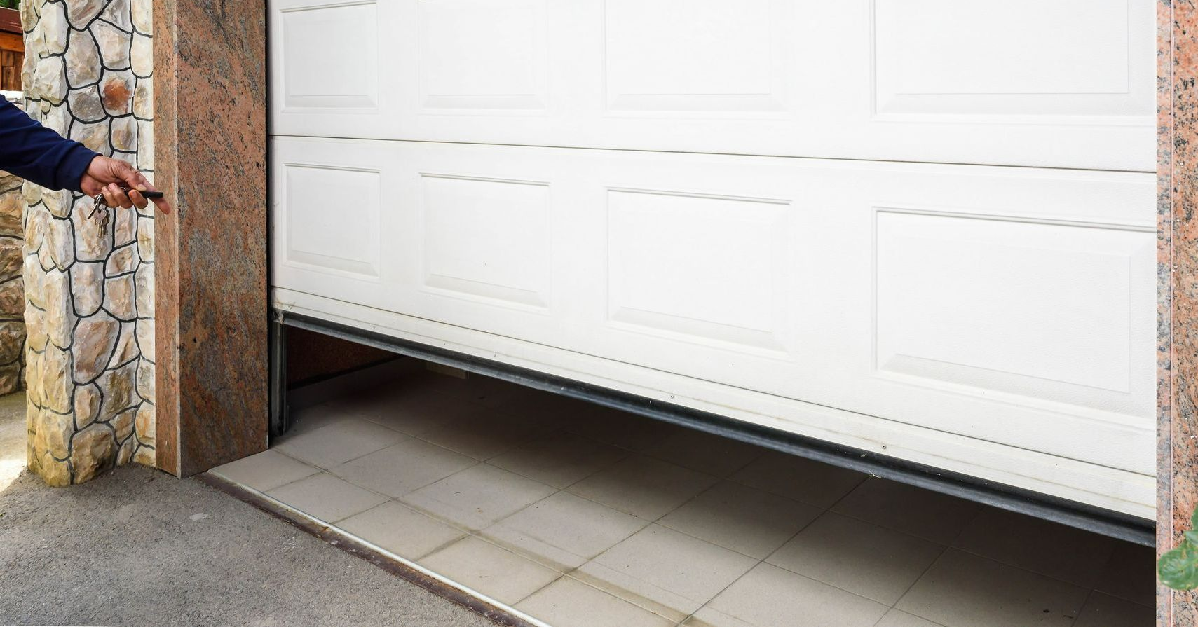 Garage door partially open, operated by a person holding a remote.