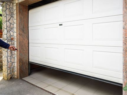 a man is opening a white garage door with a key .
