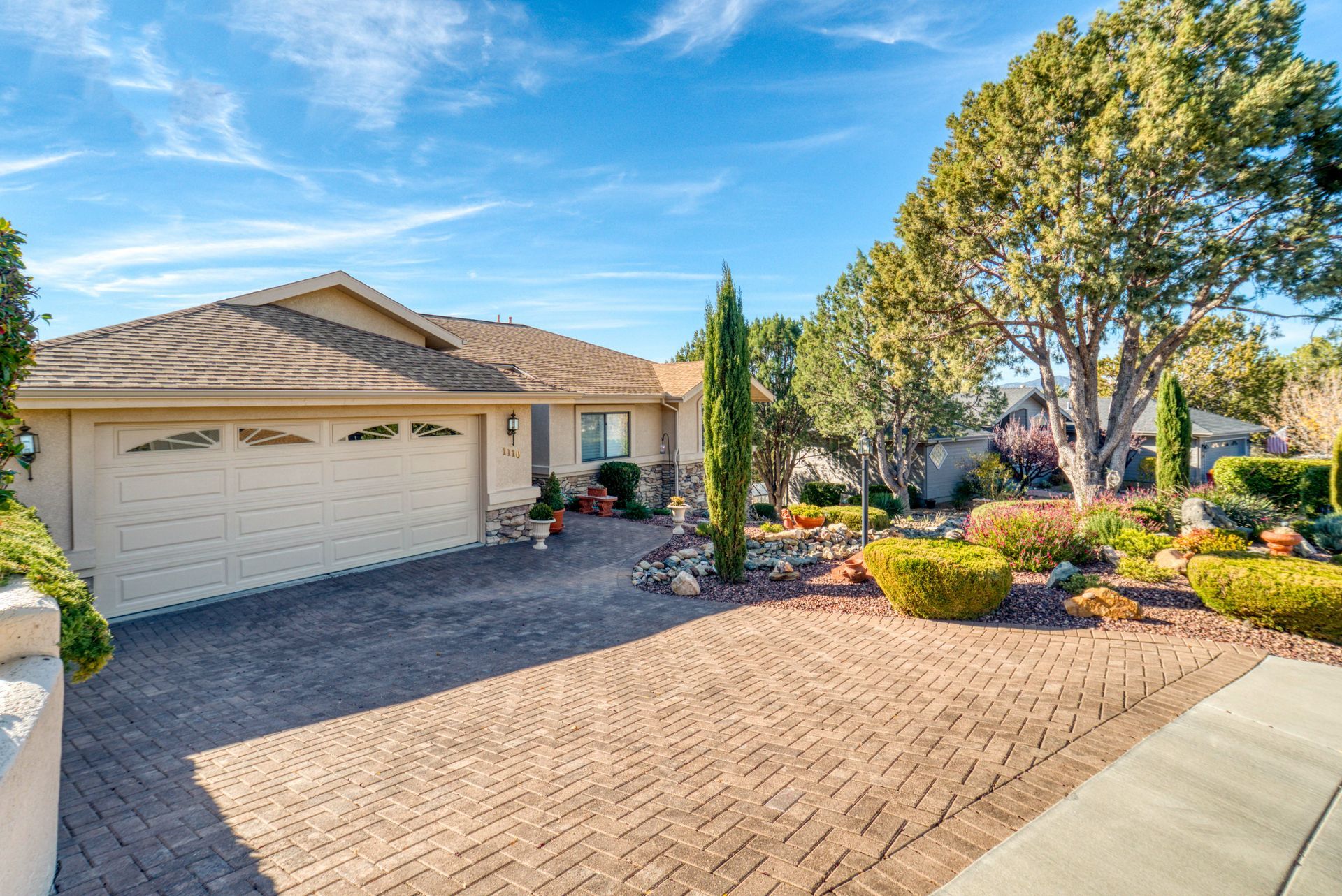 a house with a brick driveway and trees in front of it .