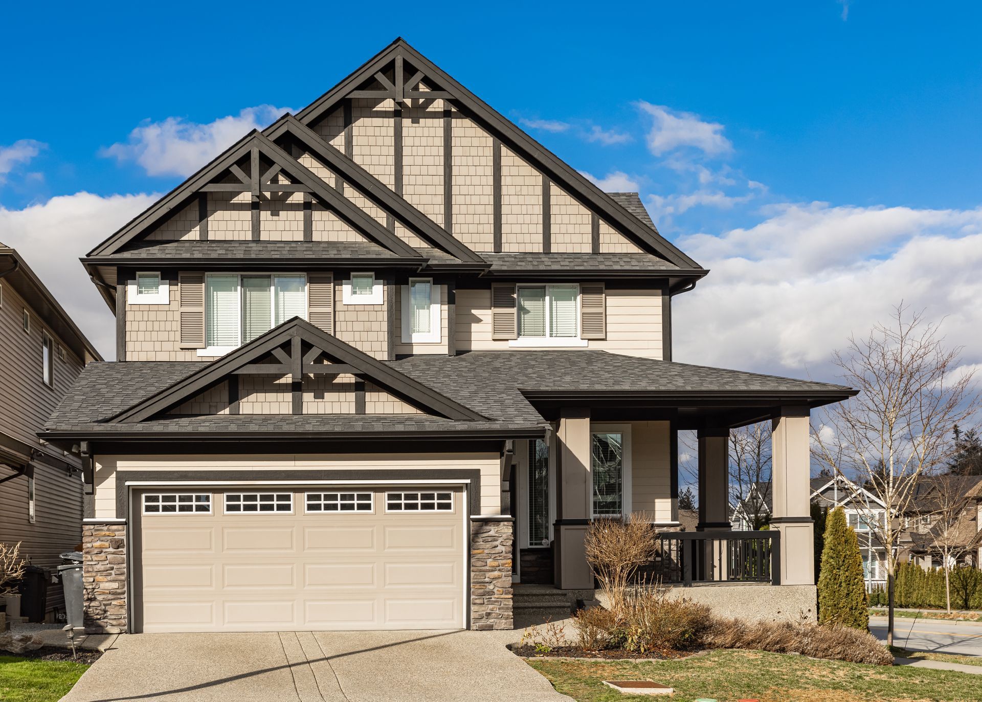 a large house with a garage and a porch on a sunny day .