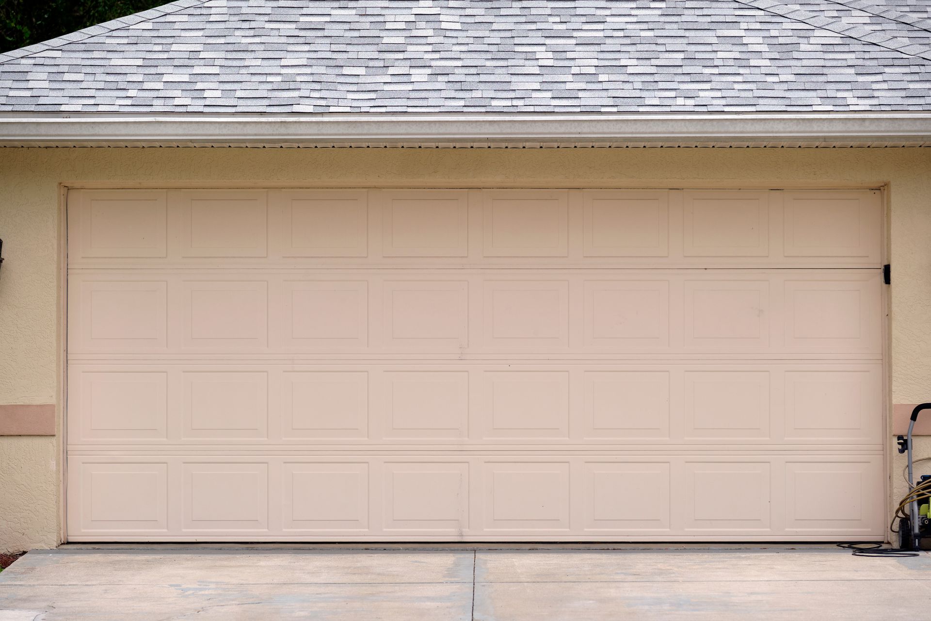 a beige garage door with a white roof