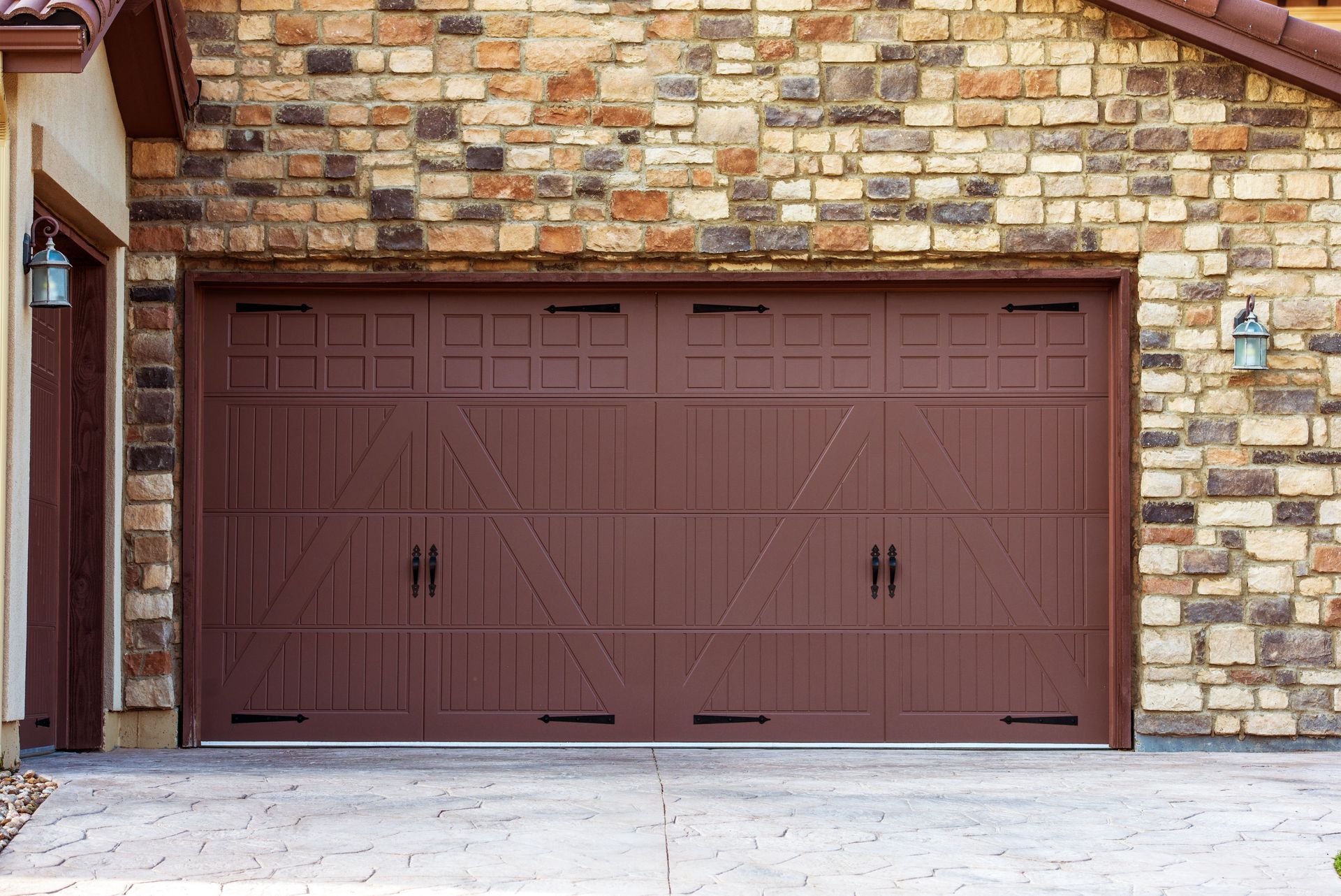 a brown garage door is sitting in front of a brick building .