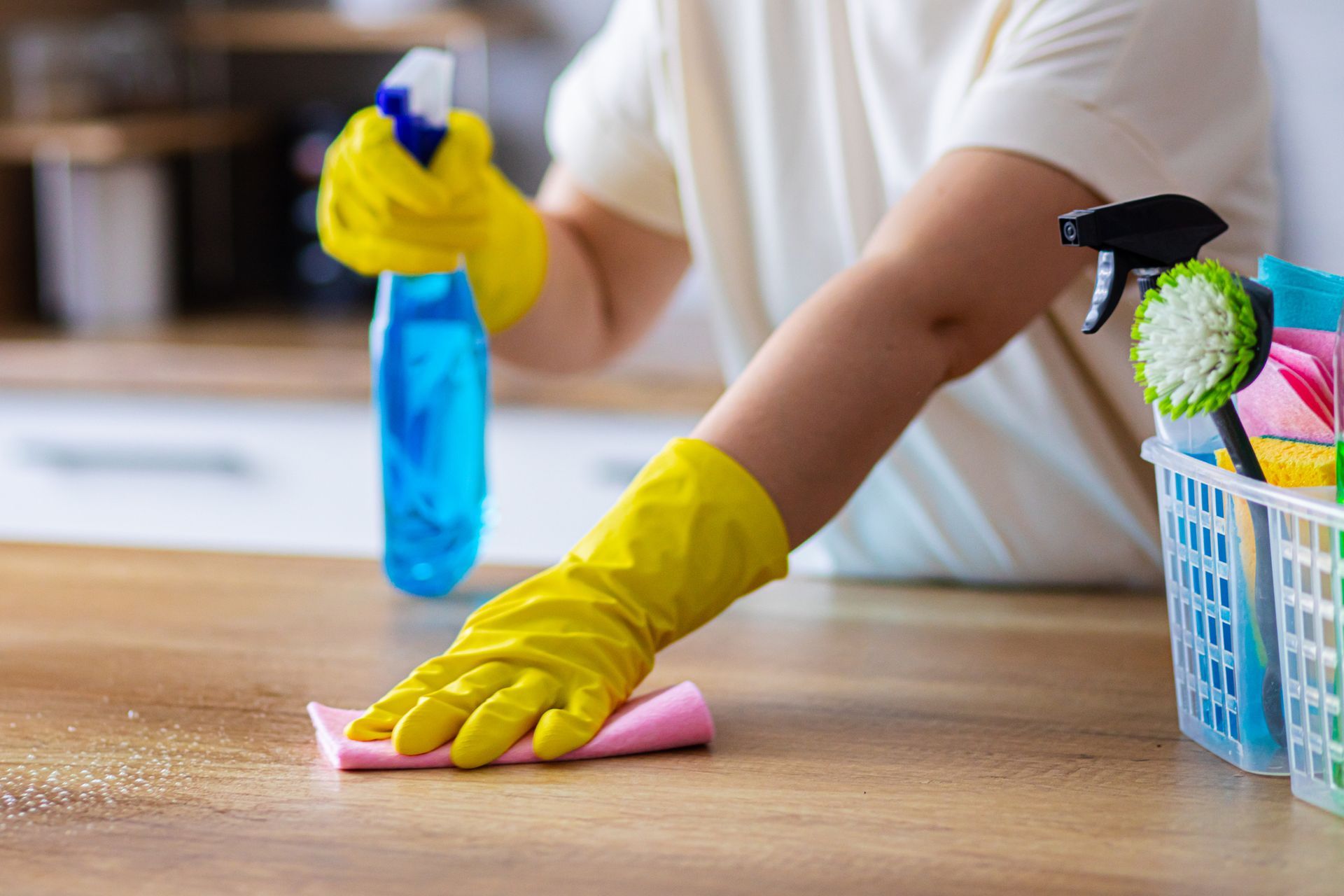 A person is cleaning the surface with a spray bottle and yellow gloves. A person is cleaning the surface with a spray bottle and yellow gloves.