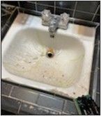 A dirty bathroom sink with water running out of it.