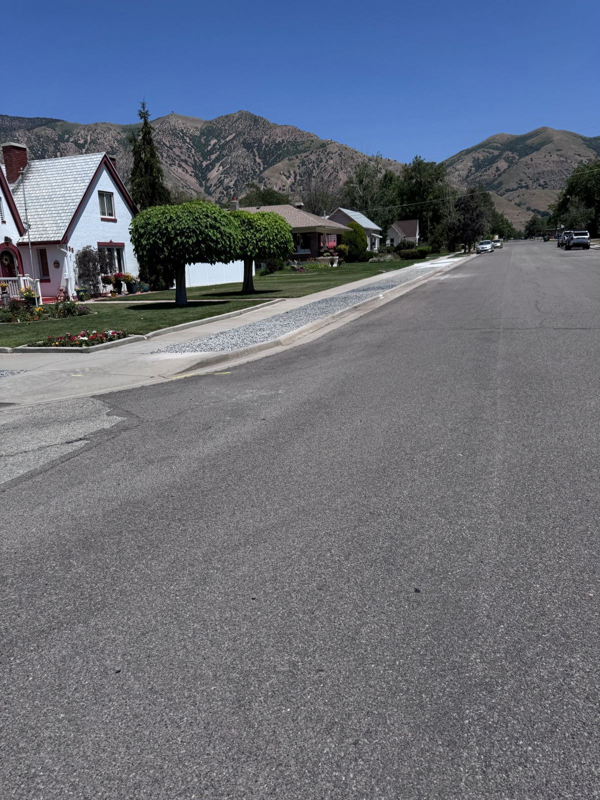 Street in residential area with houses and mountain backdrop.