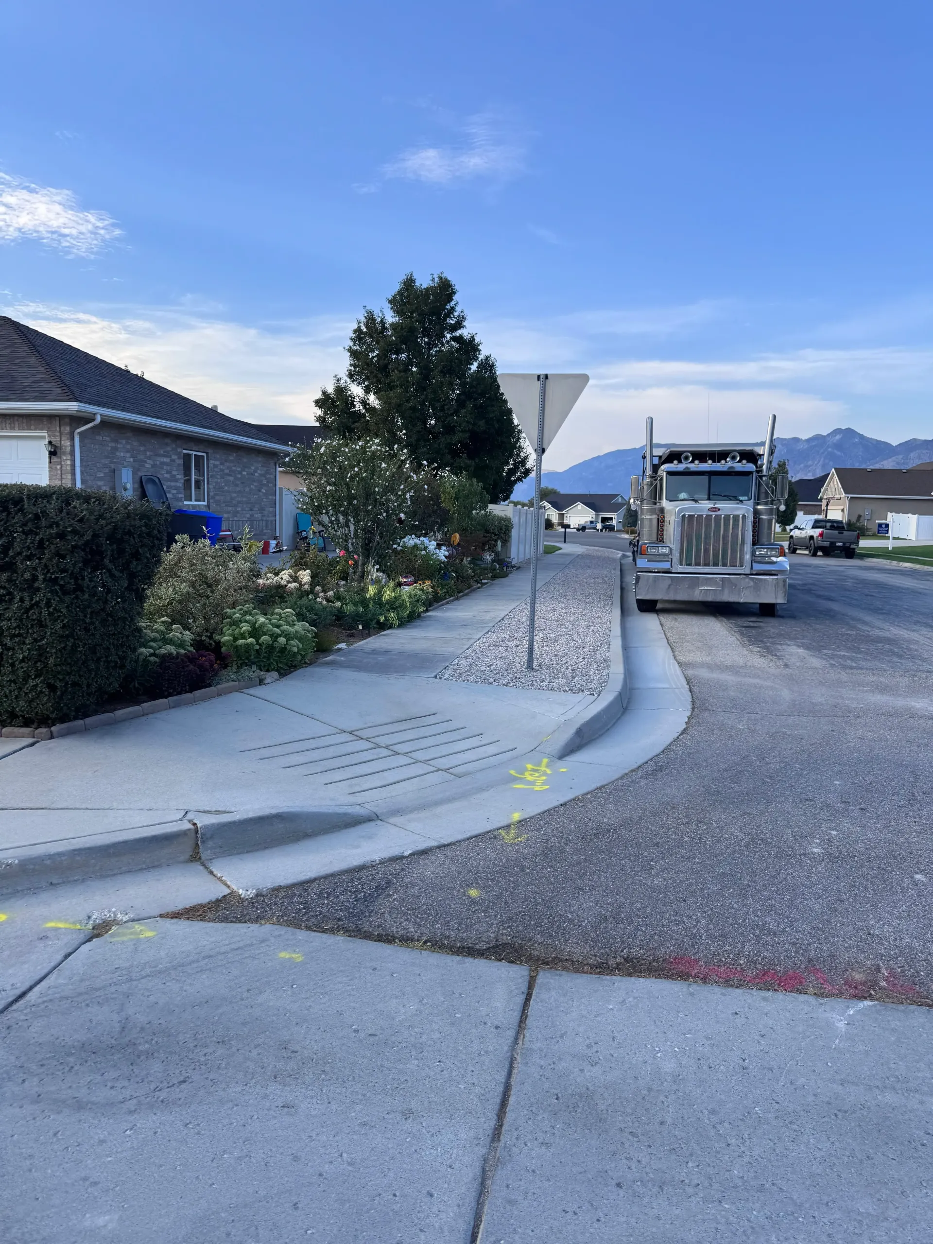 Semi-truck on a residential street with curb and sidewalk. Construction markings are visible.