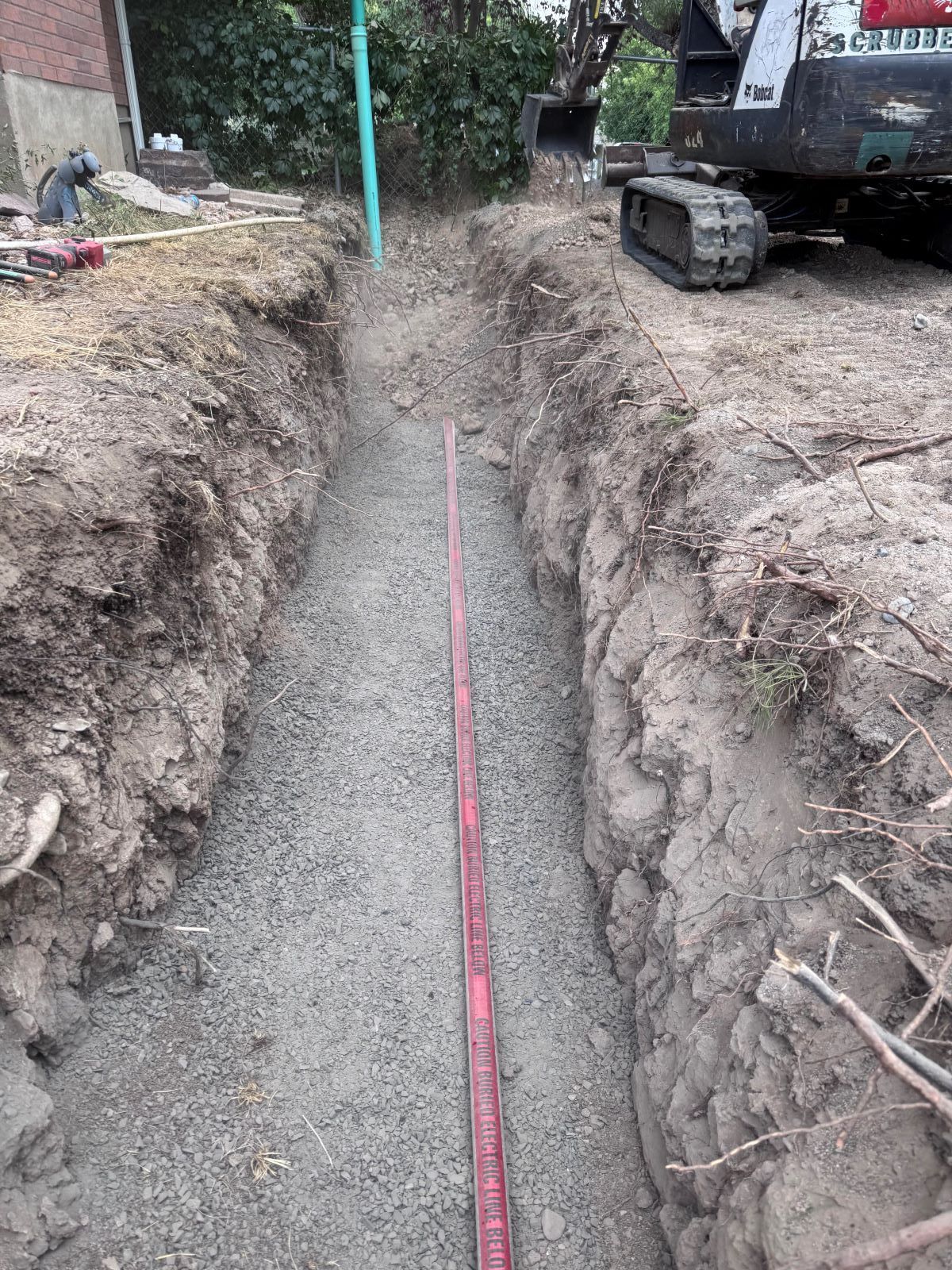 A long trench with a measuring stick, prepared for underground construction, outdoors.