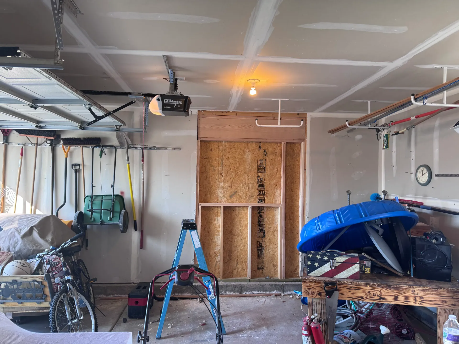 Garage interior with unfinished wooden frame, ladder, and various tools and items.