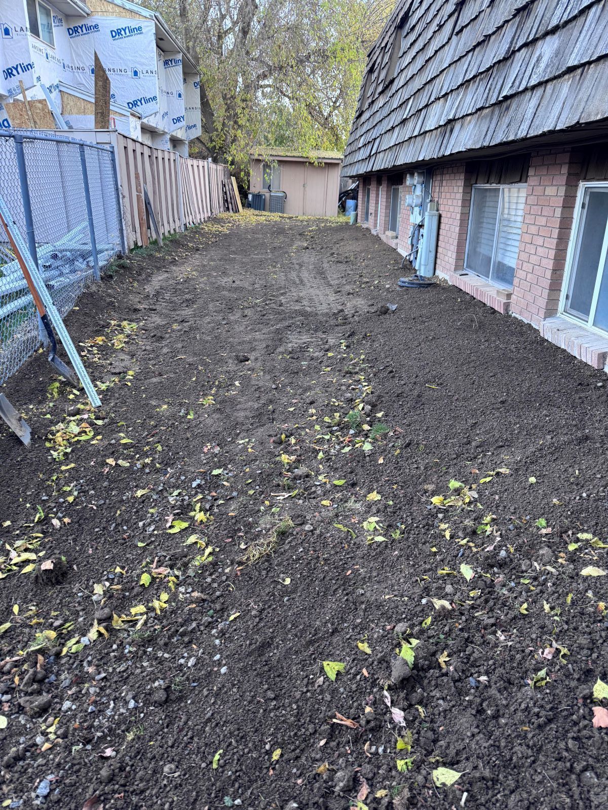 Dirt-covered yard between two buildings, preparing for planting.