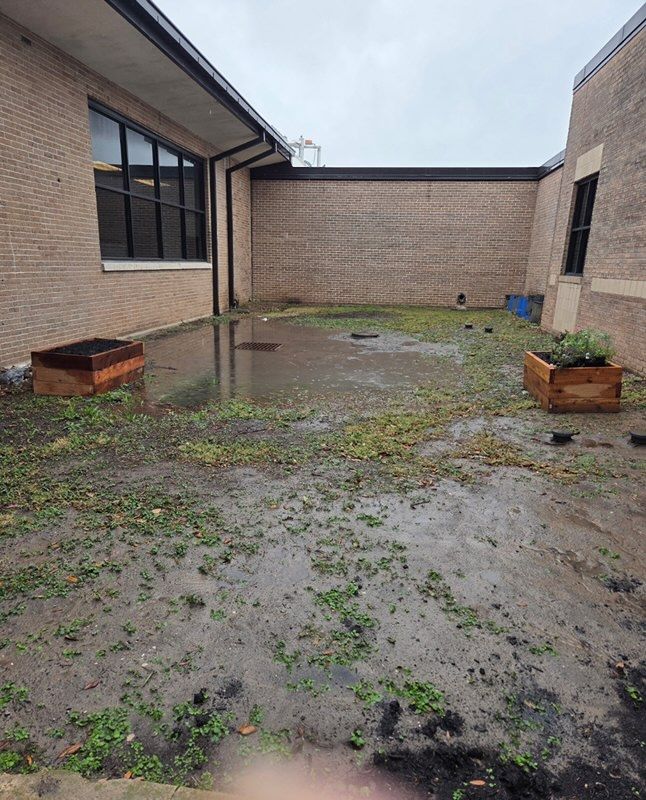 A flooded brick patio with debris. Two wooden planters sit on either side.