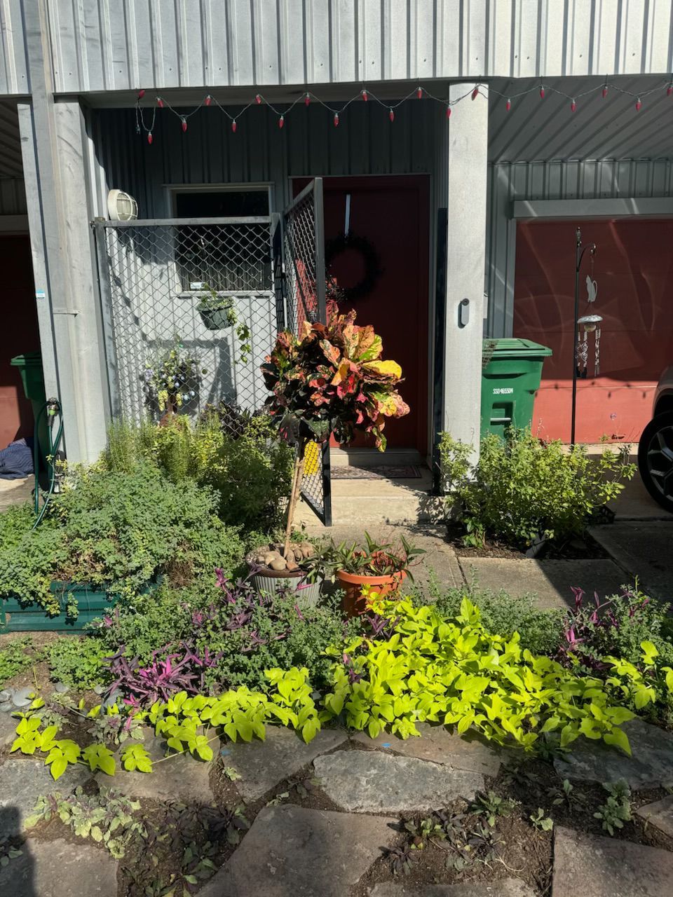 A front yard with a vibrant flower bed and a door decorated with a wreath.