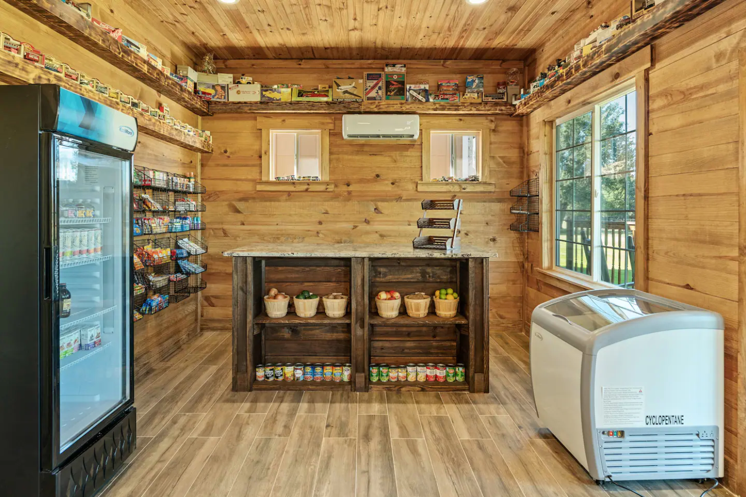 A room with a bar , refrigerators , shelves and a freezer.