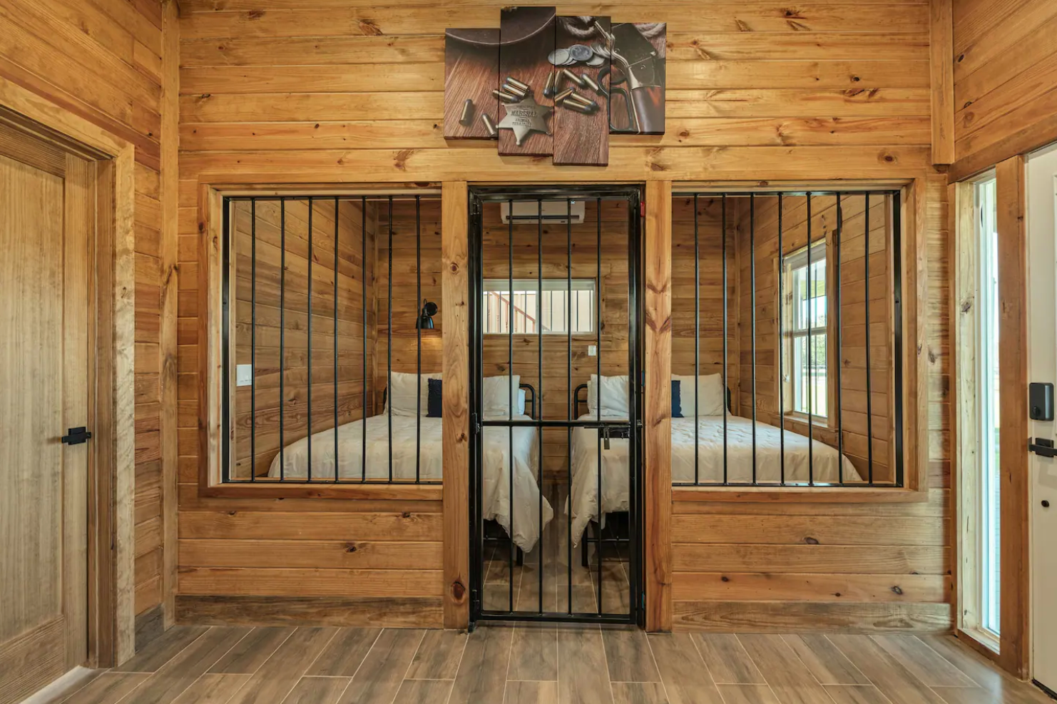 A wooden room with two beds and a prison cell.