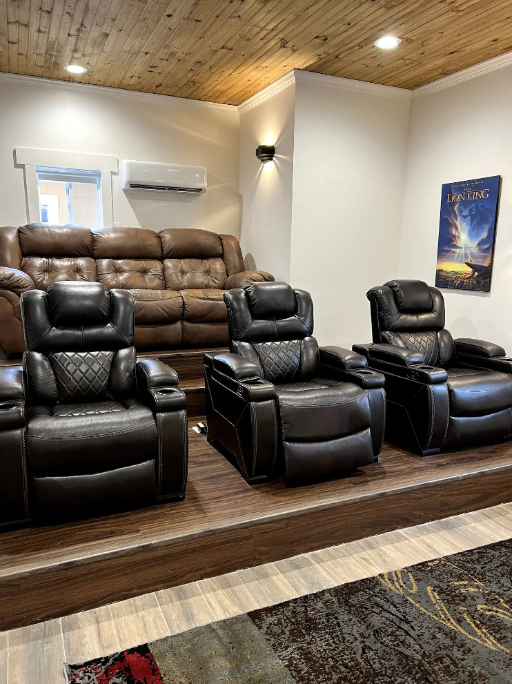 A living room with three recliner chairs and a couch.
