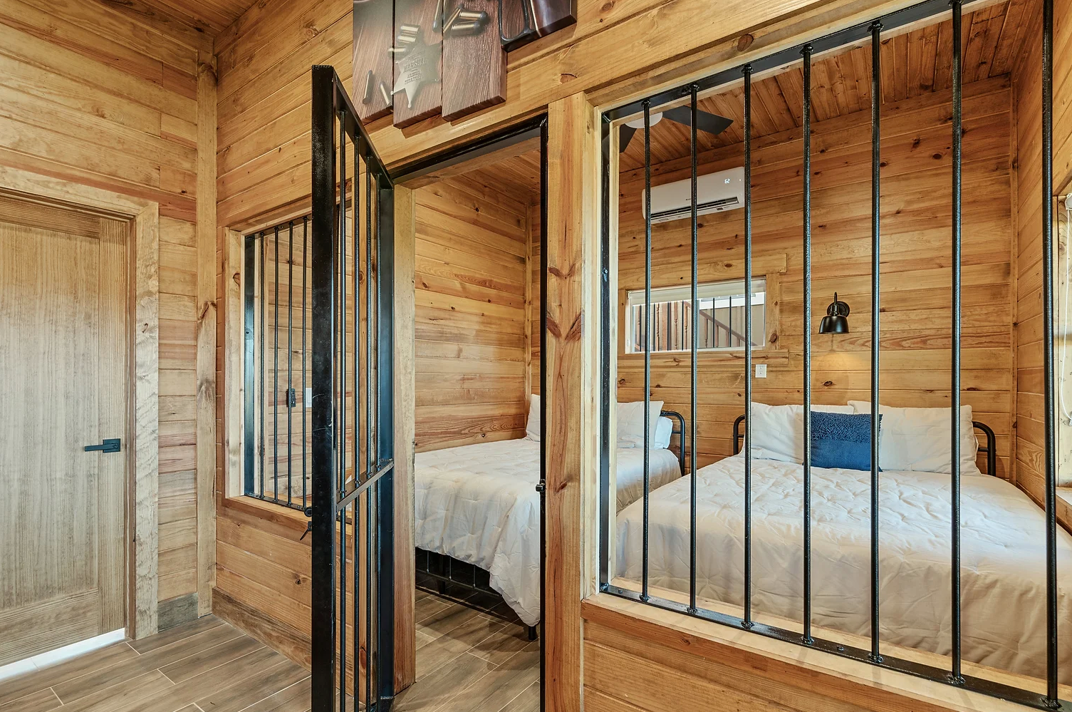 A wooden cabin with two beds and a window with bars.
