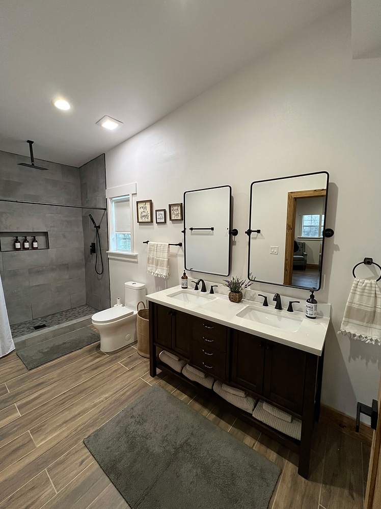 A bathroom with two sinks , a toilet , and a walk in shower.