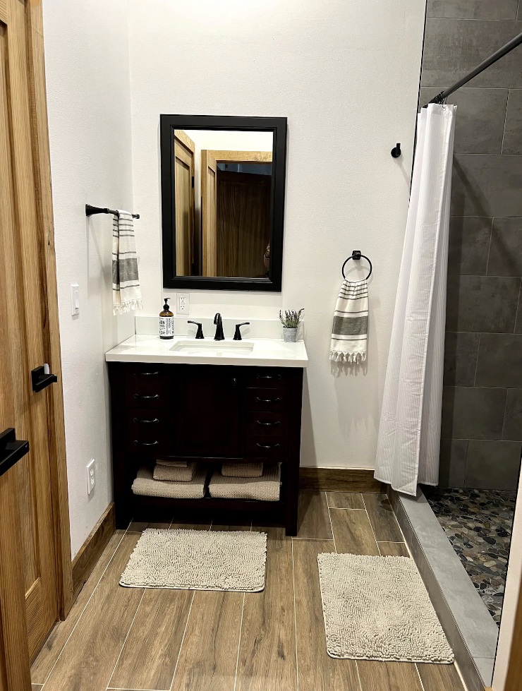 A bathroom with a sink , mirror , and shower.