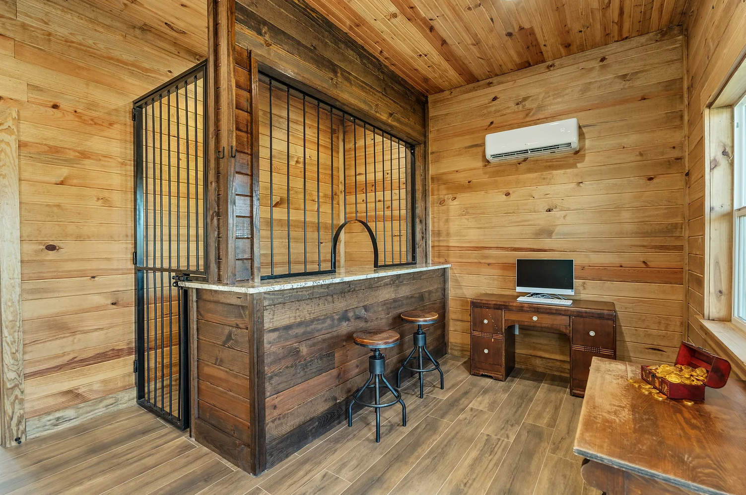 A wooden room with a bar , desk and computer.