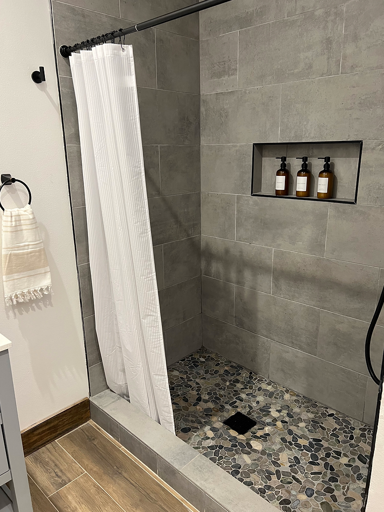 A bathroom with a walk in shower and a soap shelf.