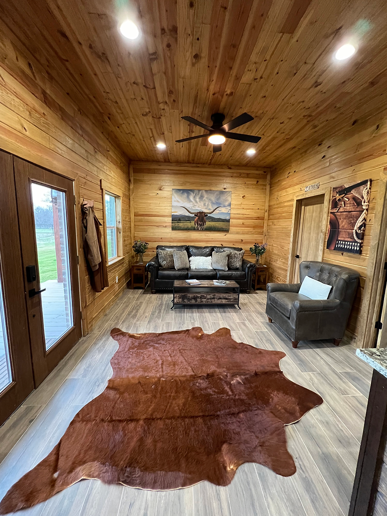 A living room in a log cabin with a cowhide rug on the floor.
