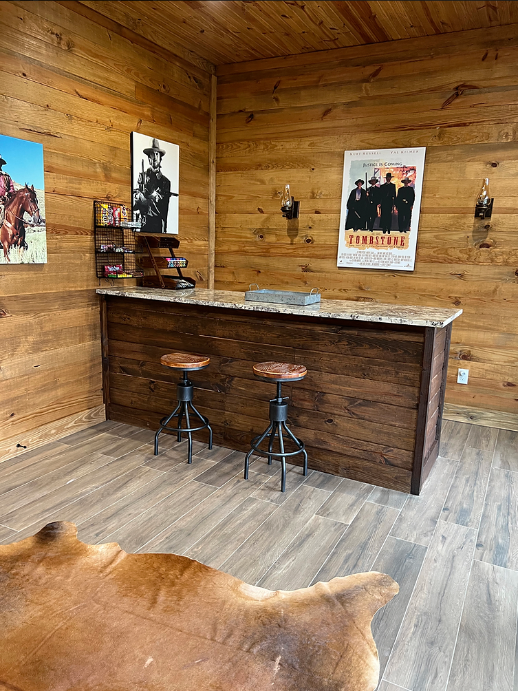 A room with a bar and stools and a cow 's fur on the floor.
