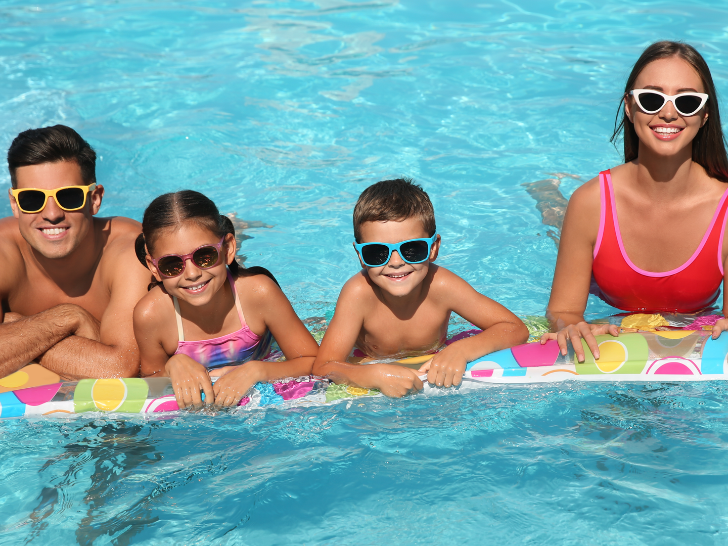 A family is laying on a raft in a swimming pool.