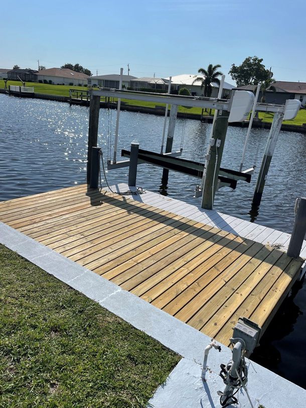Small wooden dock with railings extending over a calm waterfront under a sunny sky
