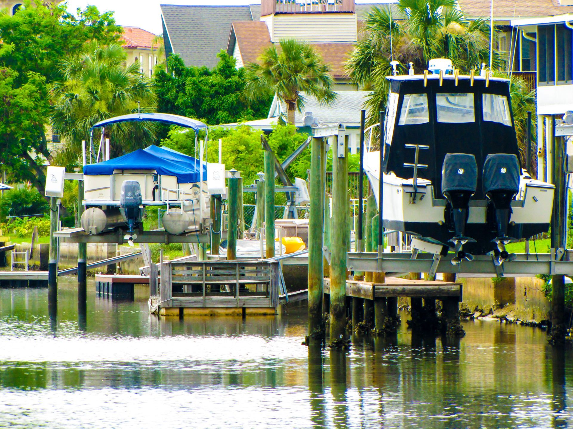 Canal with docked boats, wooden piers, and houses along a calm waterfront in bright daylight
