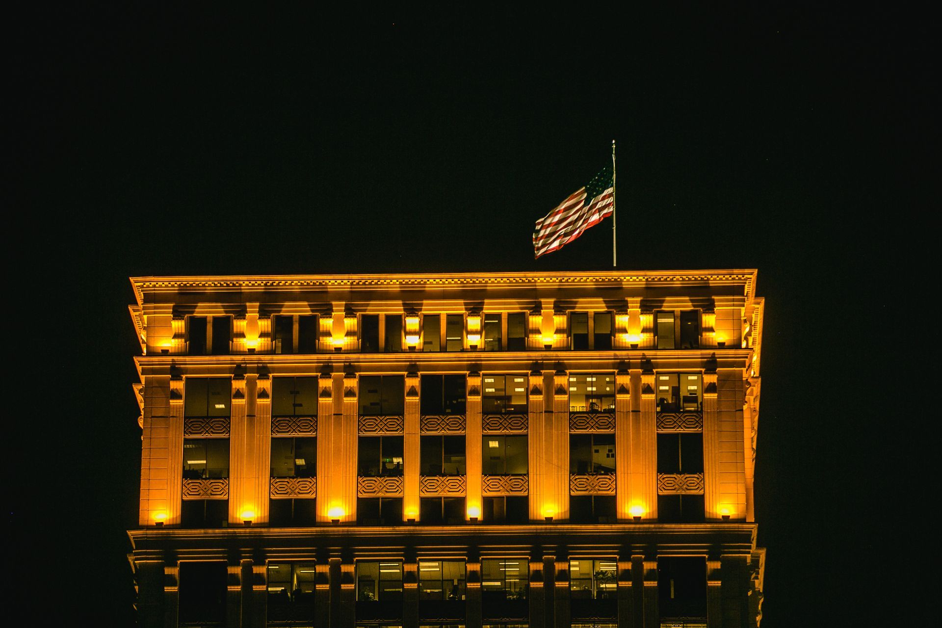 A large building with a flag on top of it at night