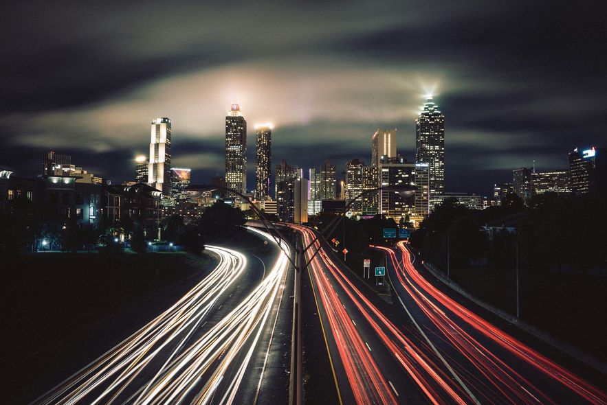 A long exposure photo of a highway at night with a city in the background.