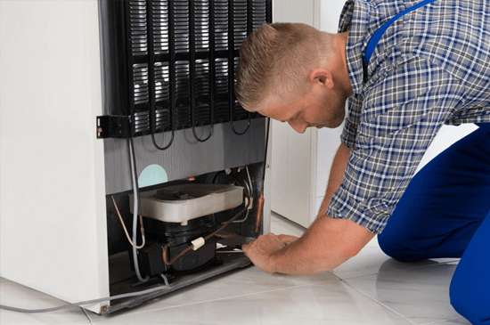 Young Male Repairman Making Refrigerator Appliance In Kitchen Room