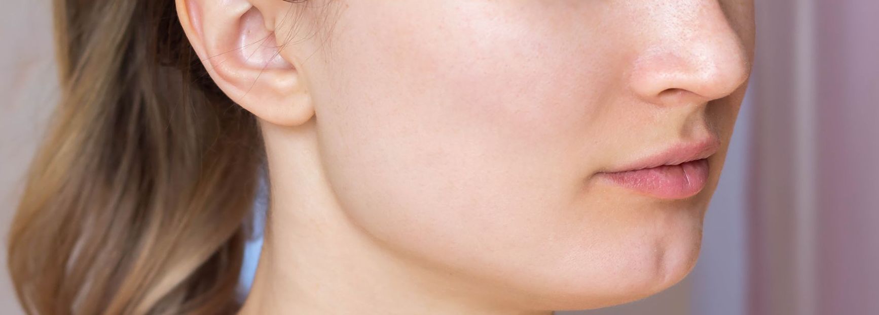 A close up of a woman 's face with a ponytail.