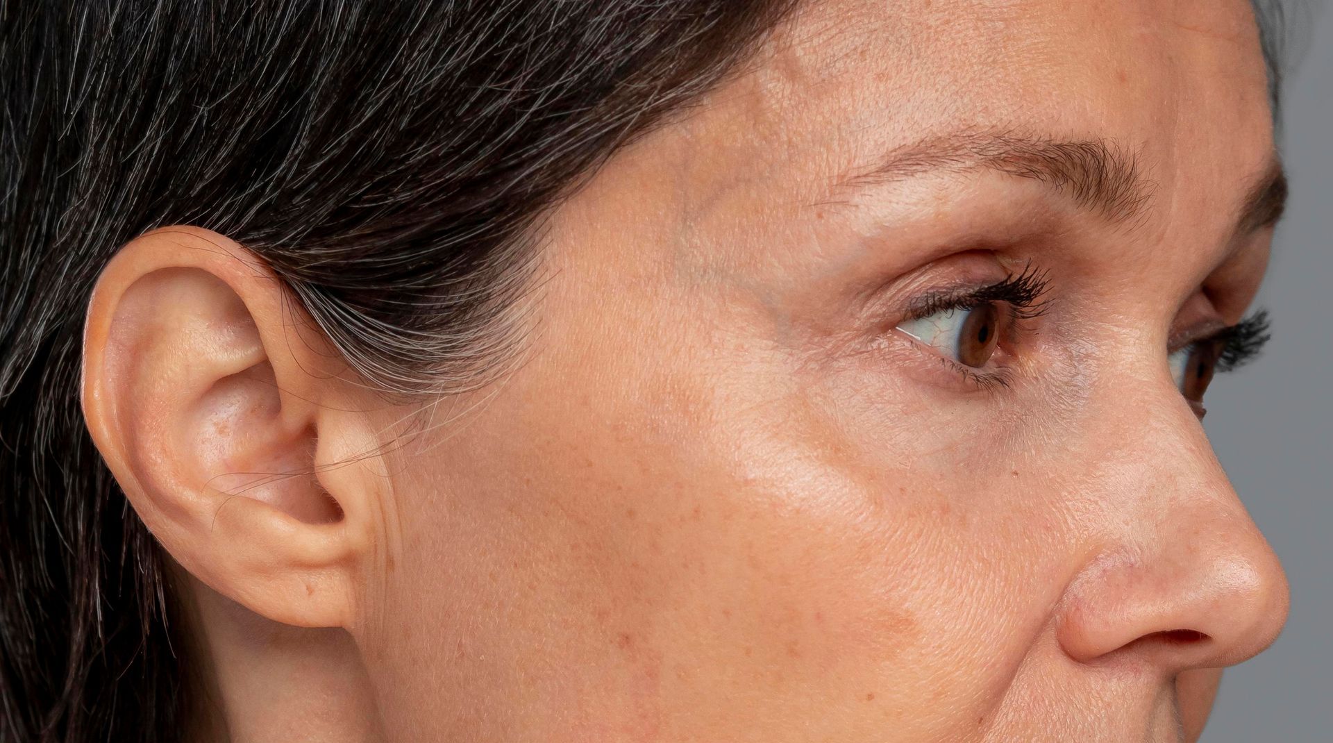 A close up of a woman 's face with a gray background.