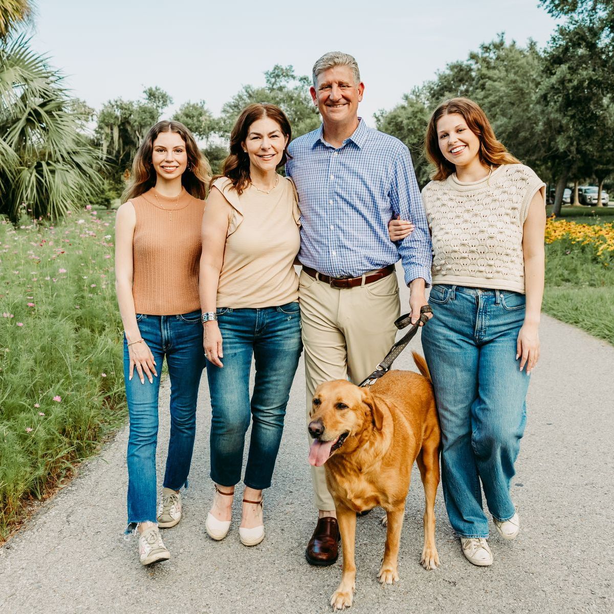A family is walking a dog down a path.