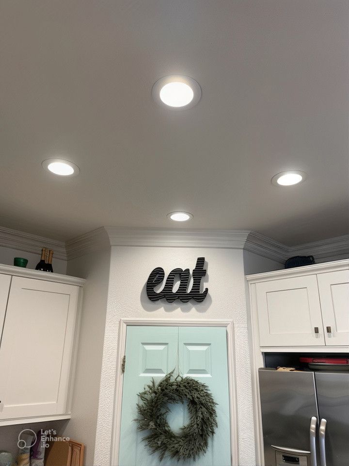 A kitchen with a sign on the wall that says eat and a wreath on the door.