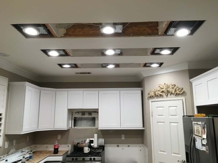 A kitchen with white cabinets and a black refrigerator