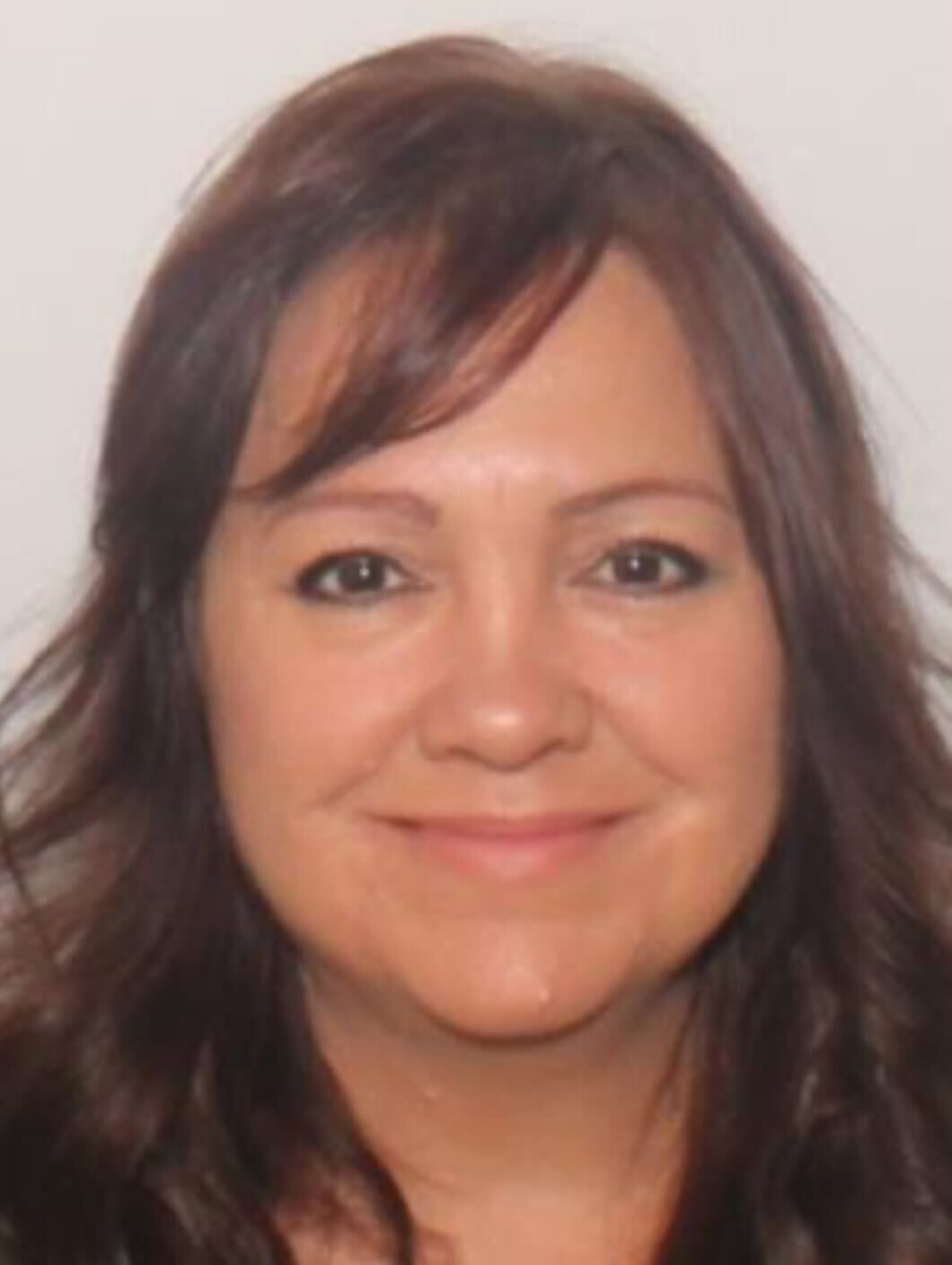 A woman with long brown hair is smiling for the camera