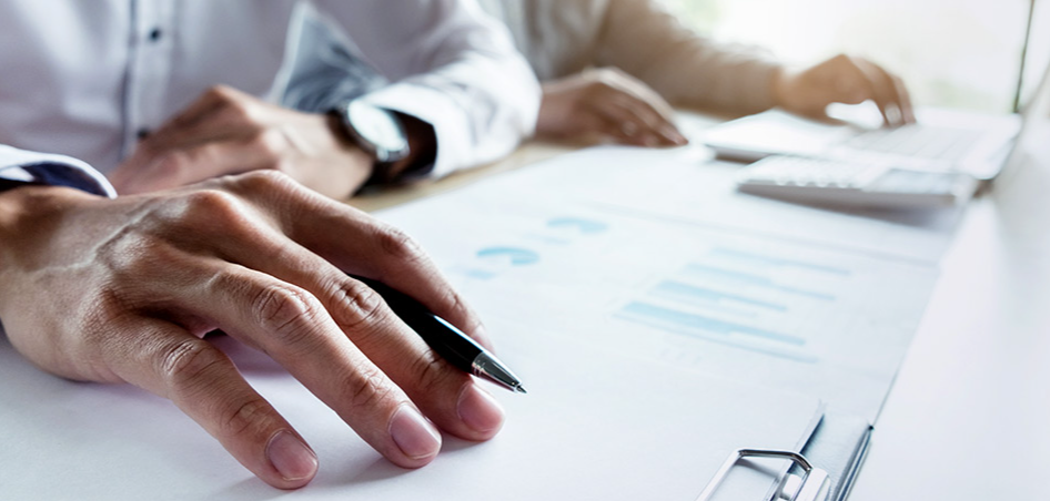 A man is sitting at a desk with a pen in his hand.