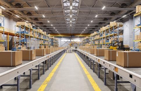 A warehouse filled with lots of cardboard boxes on conveyor belts.