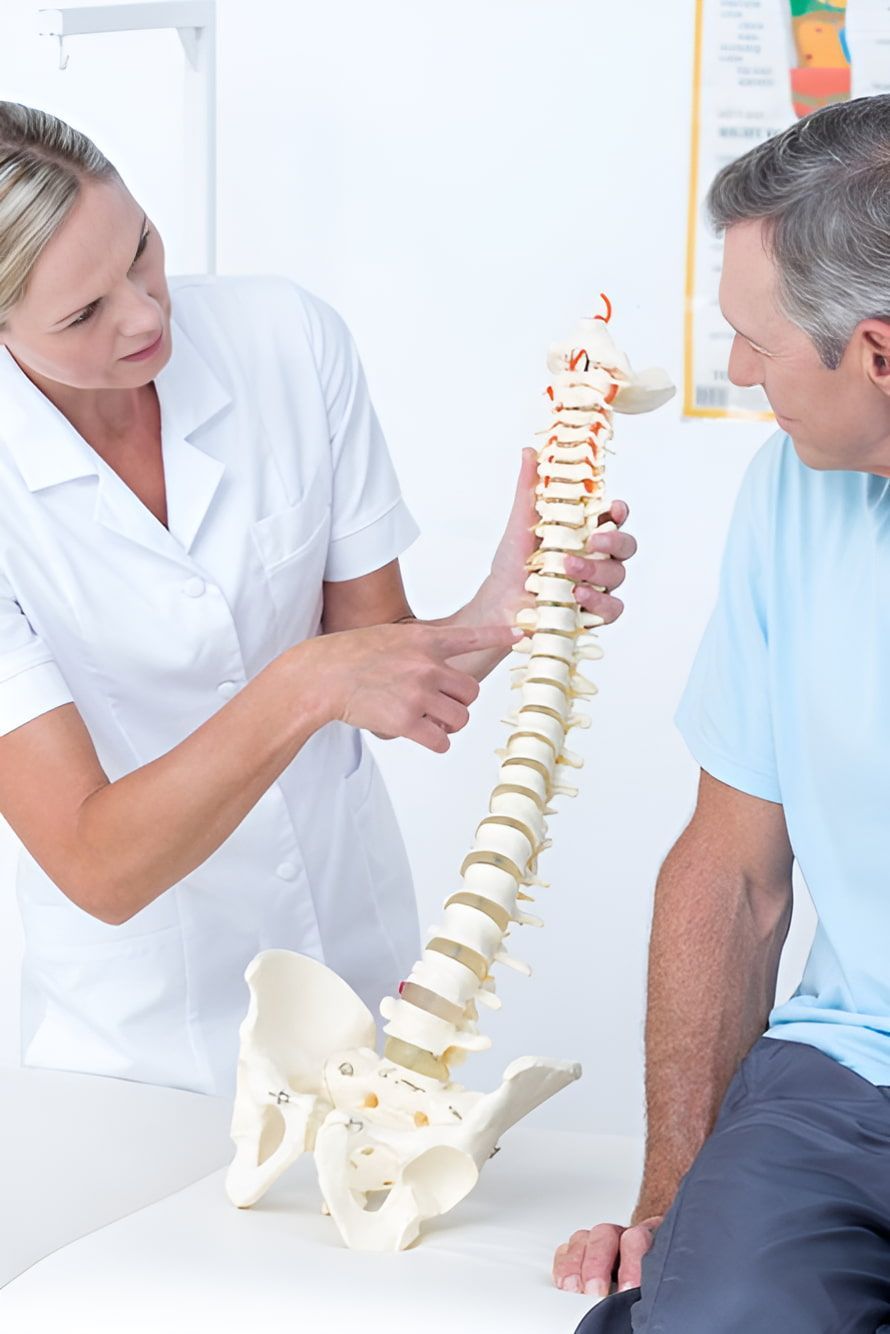 A Nurse Is Showing A Man A Model Of A Spine — Back In Motion Chiropractic & Healthcare In Innisfail, QLD