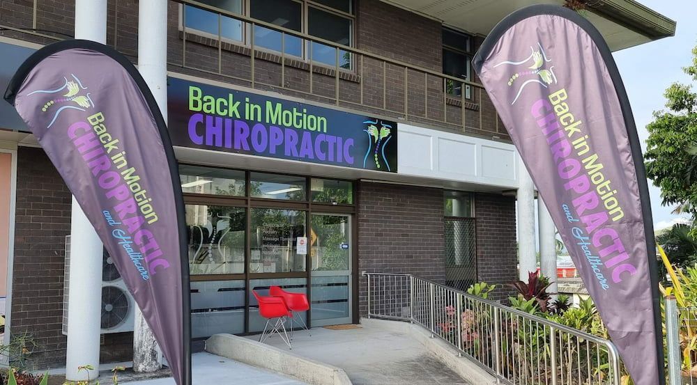 Flags Are Flying In Front Of A Building — Back In Motion Chiropractic & Healthcare In Innisfail, QLD