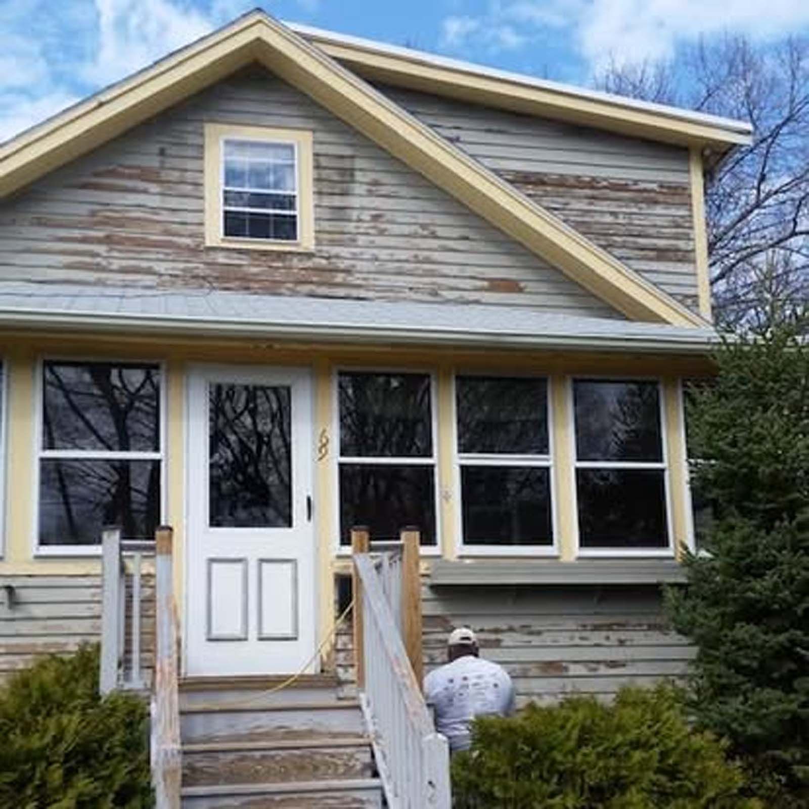A man is standing in front of a house with a white door