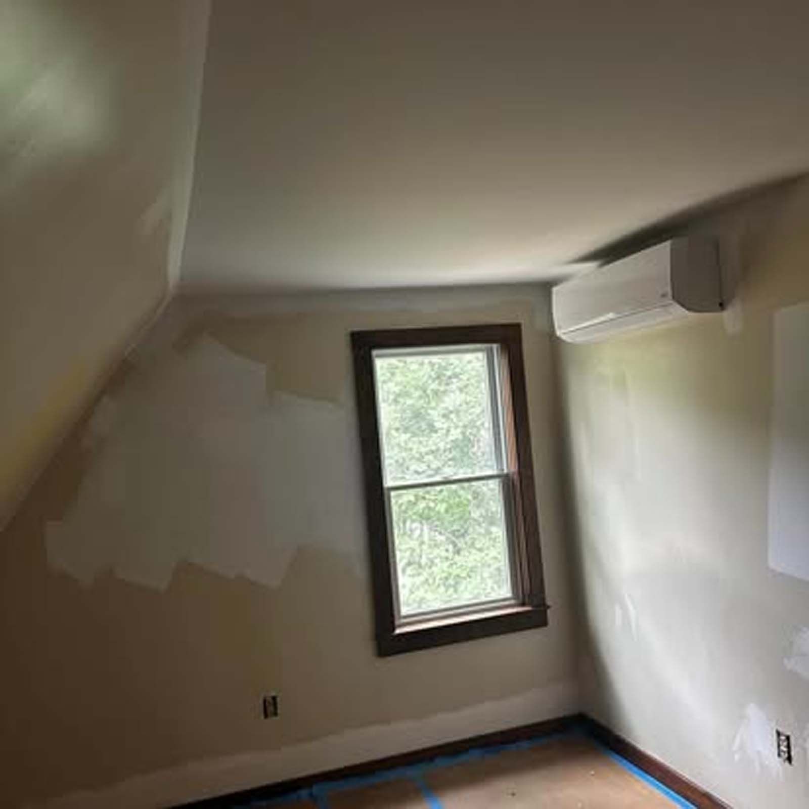 A room with a window and air conditioner on the wall.