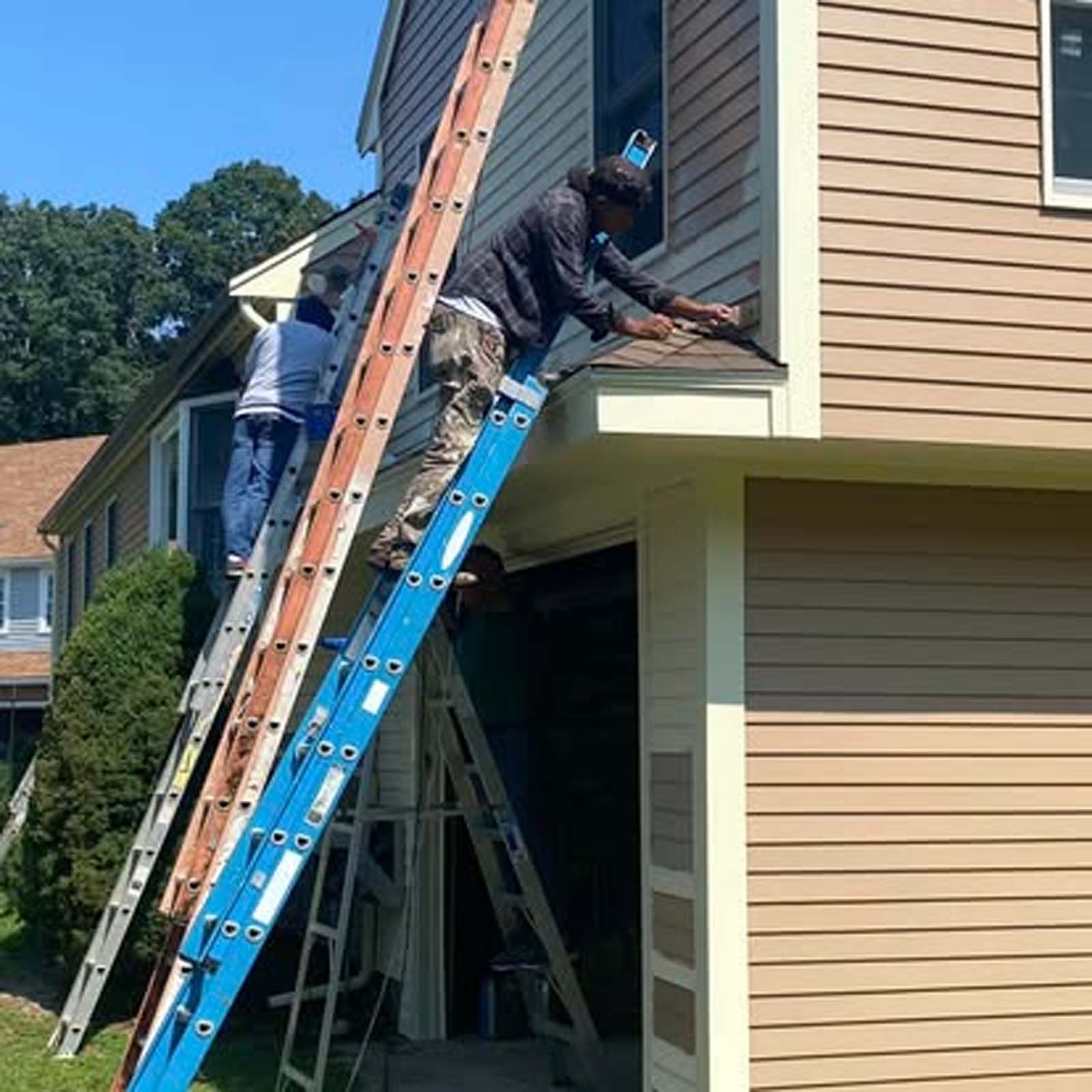 A man is standing on a ladder on the side of a house.